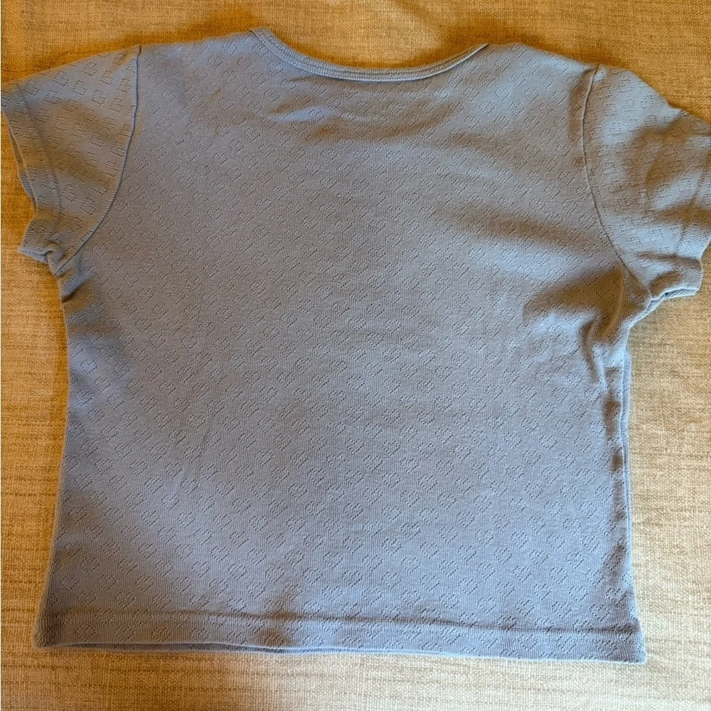 Brandy Melville Girls Light Blue Short Sleeve Top with Perforated Heart Pattern.